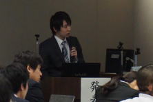 鍼灸研修生の村橋昌樹先生が講演を行っている様子。会場には聴衆が座っている。