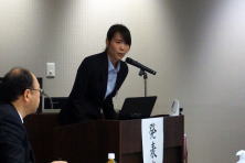研修医の女性が講演を行っている様子。前方には聴衆が座っている。