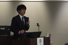 研修医の小鹿山陽介先生が講演を行っている様子。背景にはプレゼンテーション用の機器が見える。