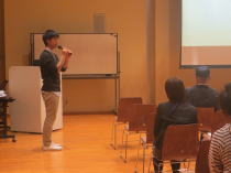 心電図セミナーで講演を行う男性と聴衆の様子。