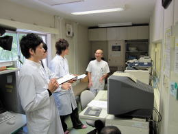 医療現場で研修を受ける学生たちが、指導医と対話している様子。