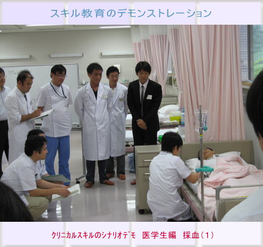医学生が患者の採血を行うスキル教育のデモンストレーションの様子。周囲には指導者や見学者が集まっている。