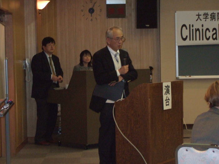 大学病院連携型高度医療人養成推進事業の講演会で、演台に立つ講師と聴衆の様子。