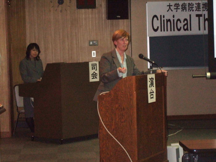 大学病院連携型高度医療人養成推進事業「Clinical Thinking」の講演会の様子。演壇で話す講師と後方でサポートするスタッフが映る。