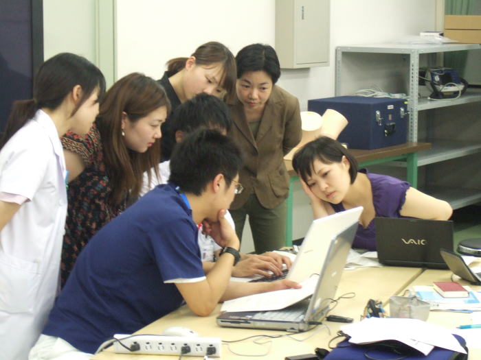 医学生たちがパソコンを囲んでプレゼンテーションの準備をしている様子。