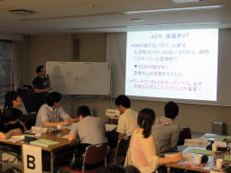 福島県立医科大学の講義中、参加者が熱心に聴講している様子。ホワイトボードには講義内容が表示されている。