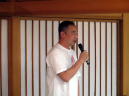 参加者がマイクを持って話している様子。背景には和風の壁が見える。