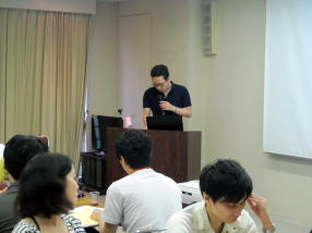 研修中の講師がプレゼンテーションを行い、参加者が聴講している様子。