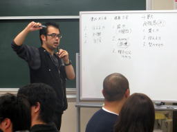 医師がホワイトボードを使って講義を行い、参加者が熱心に聴いている様子。