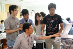 福島アドバンスド・コースでエコーを学ぶ参加者たちが、機器を操作しながら熱心に指導を受けている様子。
