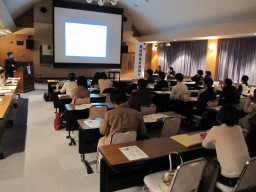 福島感染症勉強会の参加者が講義を受けている様子。スクリーンにはプレゼンテーションが映し出されている。