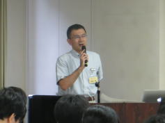 福島県立医科大学の講演会でマイクを持って話す男性の姿。参加者が聴講している様子が見える。