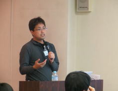 福島アドバンスド・コースで講演する男性が、参加者に向けて身体診察の重要性について話している様子。