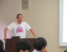 福島県立医科大学の講義で、肺のイラストが描かれたTシャツを着た講師が話している様子。受講生たちが前方で聴講している。
