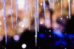 氷柱が垂れ下がる夜の風景、背景にはぼんやりとした光が広がる。