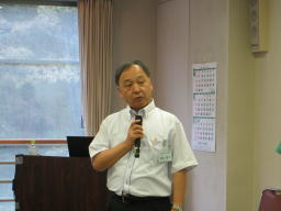 第10回診断推論セミナーで講演を行う男性がマイクを持って話している様子。背景には窓とカレンダーが見える。