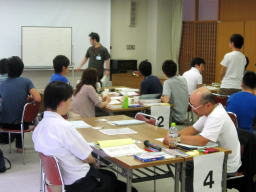 第2回診断推論セミナーで参加者が意見を交換している様子。テーブルには資料やメモが散らばり、講師がホワイトボードを使って説明している。