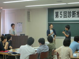 第5回診断推論セミナーで参加者が意見を交換している様子。前方で話している2人と、聴講している多くの参加者が見える。
