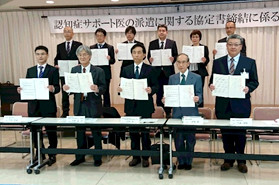 認知症サポート医の派遣に関する協定書を締結した関係者が、書類を持って記念撮影している様子。
