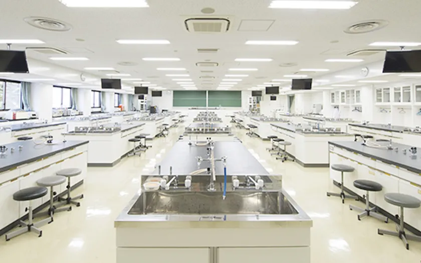 福島県立医科大学の広々とした実験室、白い作業台と椅子が整然と配置されている。