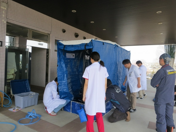 屋外用小型除染シャワーの設置訓練を行う医療スタッフの様子。