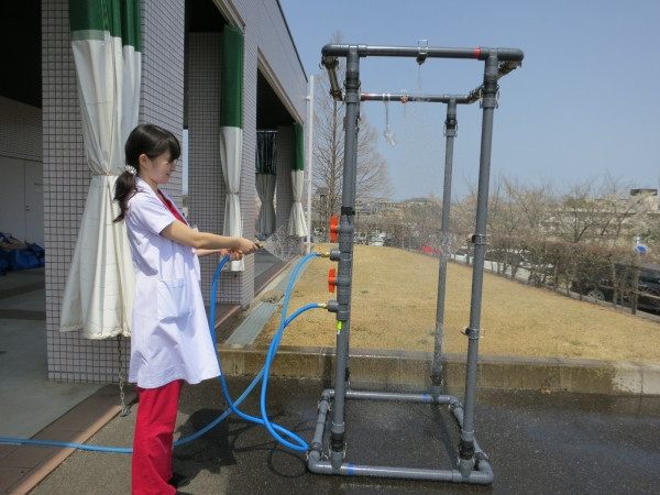 屋外用小型除染シャワーの設置訓練を行う女性スタッフの様子。