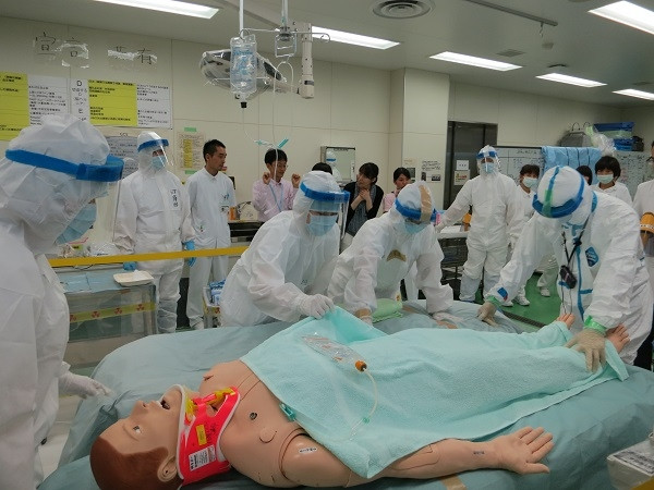 医療研修会でのシミュレーション中、医療従事者が人形に対して緊急処置を行っている様子。