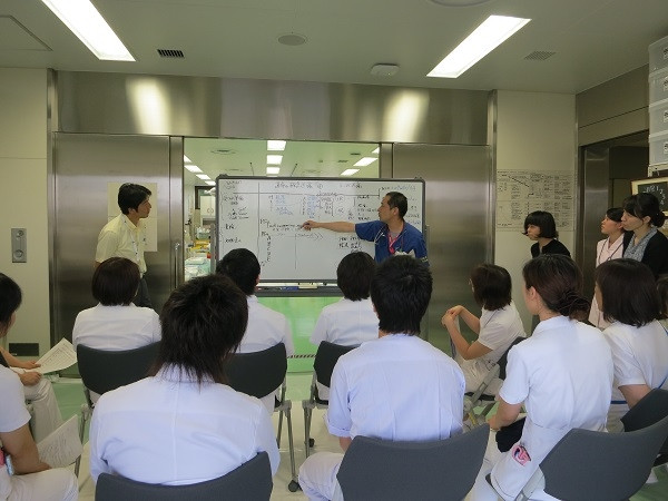 院内緊急被ばく医療研修会での講義風景。医療従事者がホワイトボードを使って説明している。
