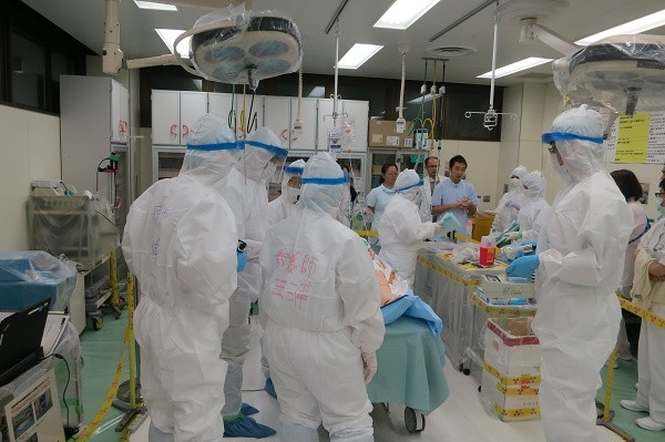 院内緊急被ばく医療研修会の様子。防護服を着た医療スタッフが集まり、訓練を行っている。