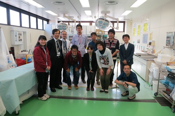 奈良県立医科大学の医学生たちが実習室で教授と共に記念撮影をしている様子。