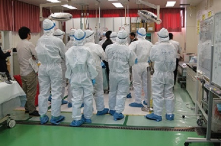 学生たちが実習中の医療現場で、白衣を着た医療従事者たちが集まっている様子。