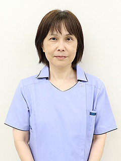 看護学部の准教授、菅野久美さんが青い制服を着て微笑んでいるポートレート。