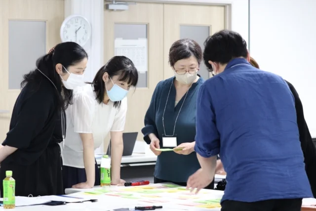 看護師特定行為研修の指導者講習会で、参加者がテーブルを囲んで資料を確認している様子。