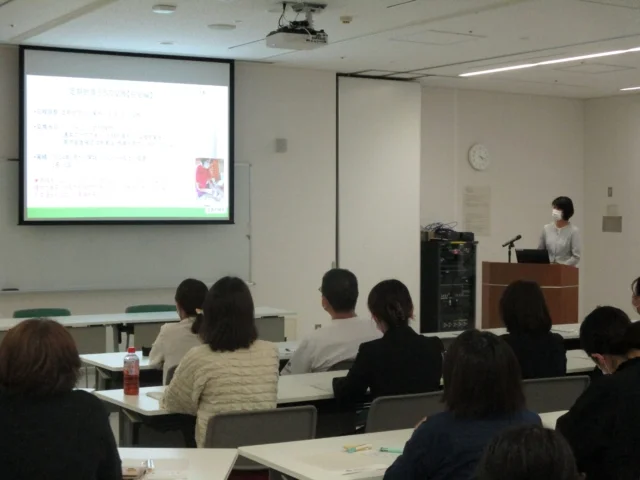 看護師特定行為普及啓発講習会で講演を行う講師と参加者の様子。