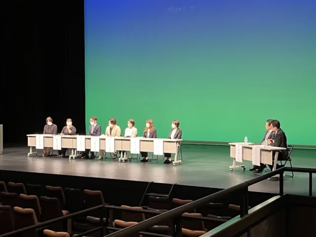 看護師特定行為普及啓発講習会のパネルディスカッションの様子。参加者がテーブルに座り、発表を行っている。