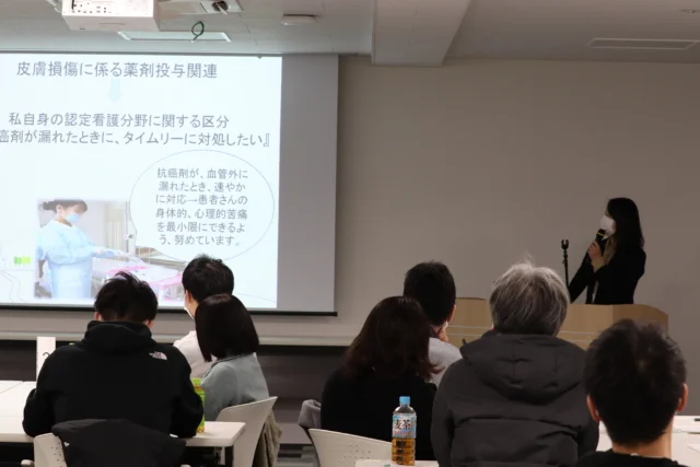 看護師特定行為フォローアップセミナーで講演を行う女性と参加者たちの様子。