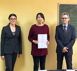 ロシア国立メーチニコフ北西医科大学で修士課程を修了した加藤美喜子さんが、証明書を持って記念撮影をしている様子。左側には女性、右側には男性が立っている。