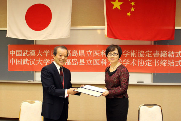 中国武漢大学医学部との学術交流協定の締結式で、協定書を手にする菊地理事長と熊副医学部長。