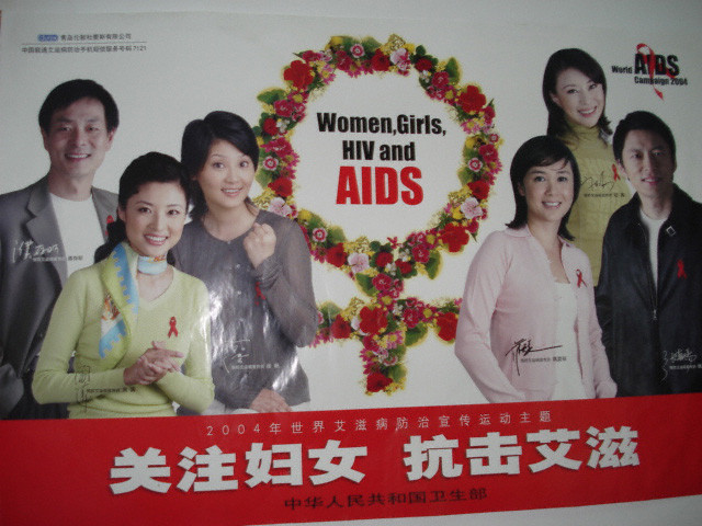 複数の男女が写ったポスターで、HIVとAIDSに関する啓発を目的とし、赤いリボンを身につけています。背景には花のリースがあります。