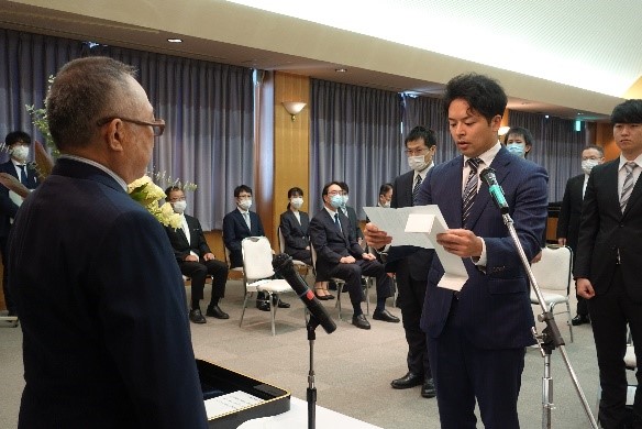 大学院医学研究科の入学式で、スピーチをする新入生とそれを聞く教員や学生たちの様子。