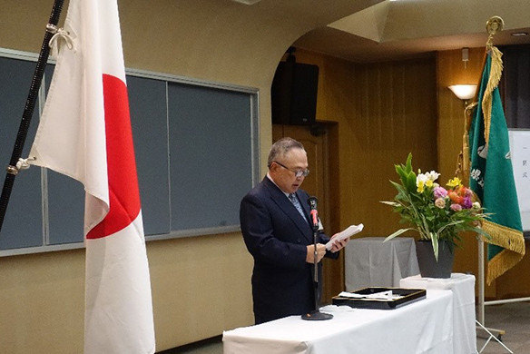 大学院医学研究科の入学式でスピーチをする竹之下学長と花が飾られた壇上の様子。
