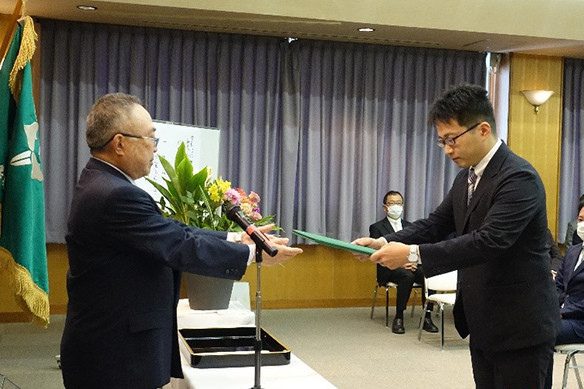 大学院の学位記授与式で、卒業生が学位を授与される瞬間を捉えた写真。