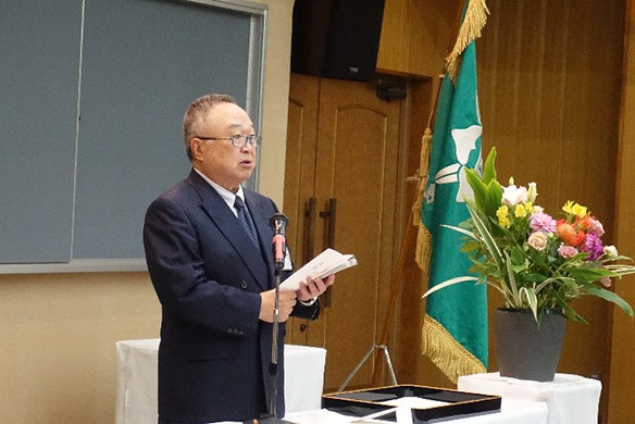 大学院の学位記授与式でスピーチをする竹之下学長と華やかな花が飾られたテーブルの様子。