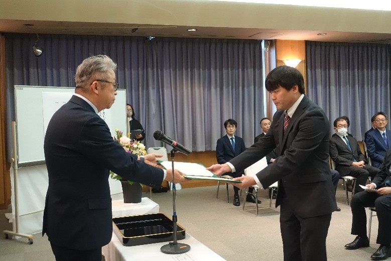 大学院の学位記授与式で、卒業生が学位を授与される瞬間を捉えた写真。