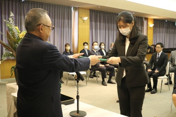 大学院の学位記授与式で、卒業生が学位を授与される瞬間を捉えた写真。