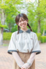 緑の木々に囲まれたキャンパスで微笑む学生の姿。