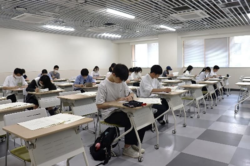 教室で机に向かい集中して答案を書いている様子。