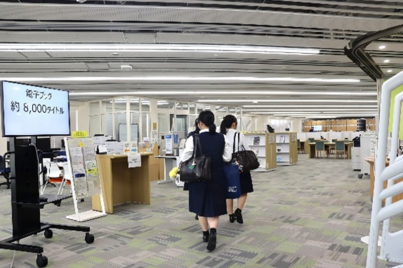 図書館内を歩く3人の学生