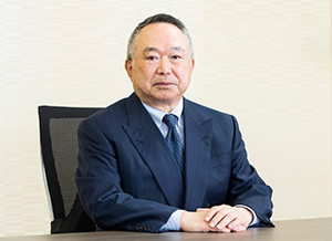 福島県立医科大学の理事長兼学長がスーツ姿で座っている写真。