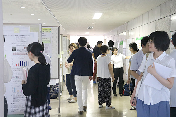 廊下で実施されるポスターセッションに参加する学生や医療関係者たち。研究内容の説明に熱心に耳を傾けている様子。